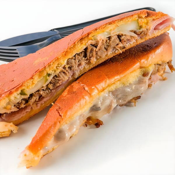 A sliced Cubano sandwich from Cubano Bros, revealing roasted pork, ham, cheese, and pickles.